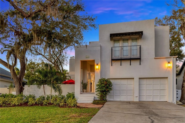 view of front of house featuring a garage, concrete driveway, a balcony, fence, and stucco siding