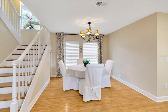 dining space with a notable chandelier and light hardwood / wood-style flooring