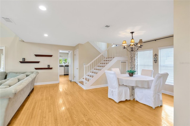 dining room with light wood-type flooring and an inviting chandelier