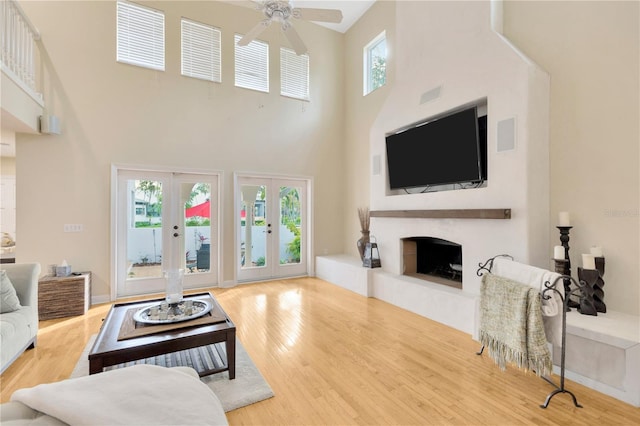 living room with ceiling fan, a high ceiling, wood-type flooring, and french doors