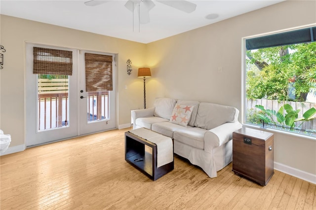 living room featuring light wood-type flooring, ceiling fan, and french doors