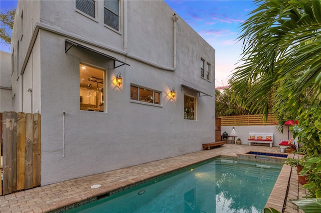 back house at dusk with a fenced in pool