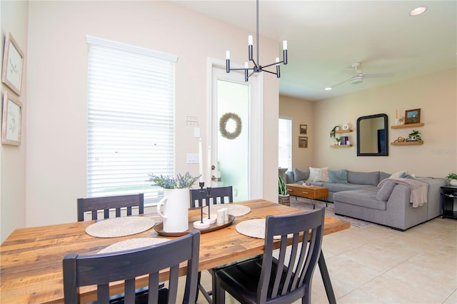 dining space with light tile patterned floors and ceiling fan with notable chandelier