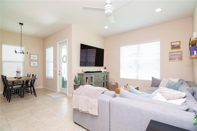 living area featuring light tile patterned floors, baseboards, ceiling fan with notable chandelier, and recessed lighting