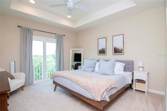 bedroom featuring light carpet, baseboards, and a raised ceiling