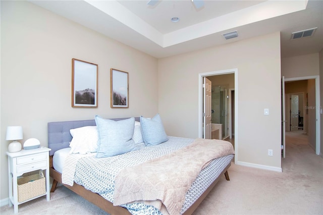 bedroom with light carpet, a raised ceiling, visible vents, and baseboards