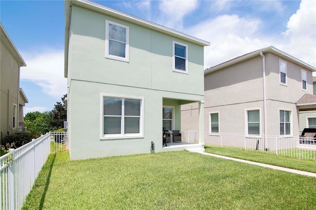 back of house featuring a lawn, a fenced backyard, and stucco siding