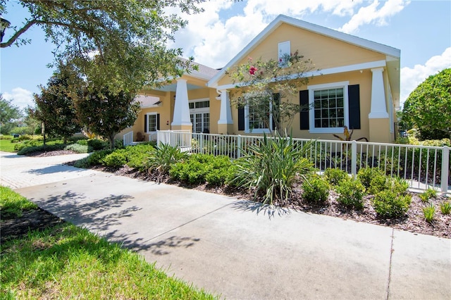 view of front of home with covered porch, a fenced front yard, and stucco siding