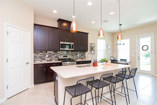 kitchen featuring visible vents, decorative backsplash, appliances with stainless steel finishes, a sink, and a kitchen breakfast bar