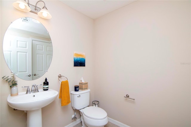 half bathroom featuring baseboards, a sink, and toilet