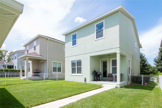 back of property with stucco siding, fence, a patio, and a yard