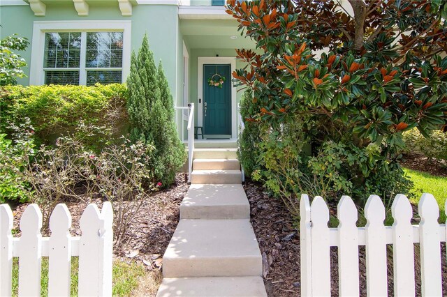 view of exterior entry featuring fence and stucco siding