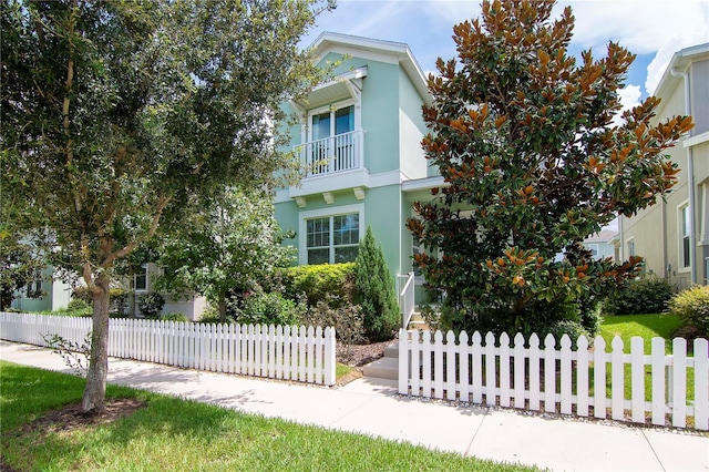 view of front of property with a fenced front yard, a balcony, and stucco siding