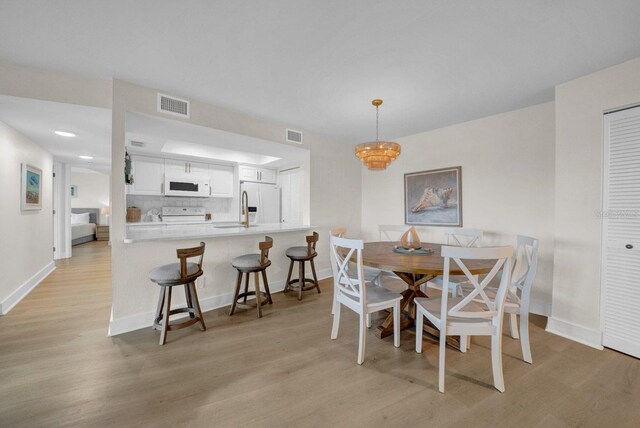 dining space featuring light wood-style floors, visible vents, and baseboards