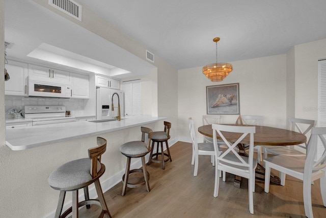 kitchen featuring light wood-style floors, white appliances, visible vents, and a sink