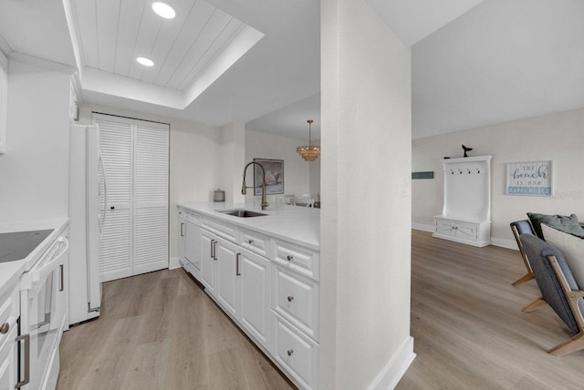 kitchen featuring white appliances, white cabinetry, light wood finished floors, and a sink