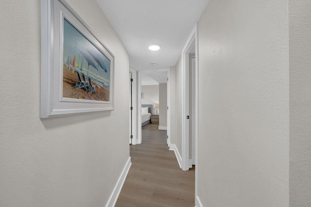 corridor with wood finished floors and baseboards