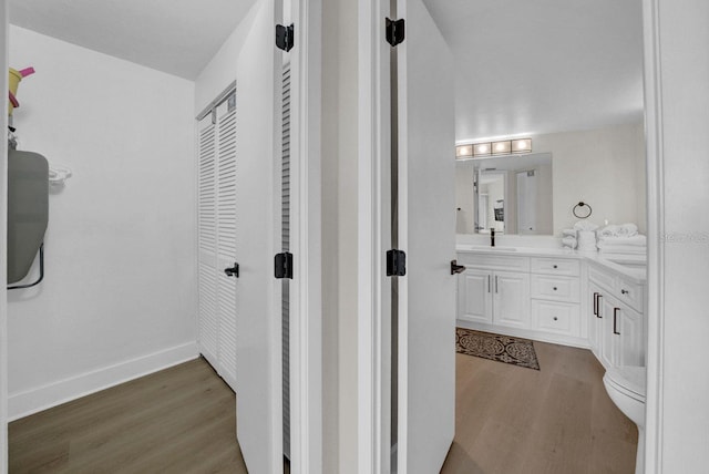 bathroom with toilet, baseboards, wood finished floors, and vanity