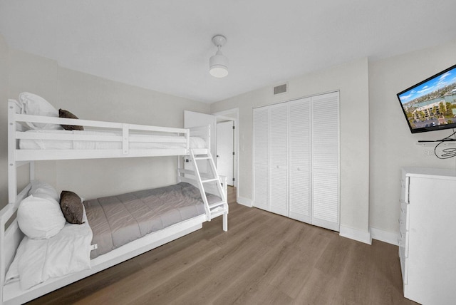 bedroom featuring visible vents, a closet, baseboards, and wood finished floors