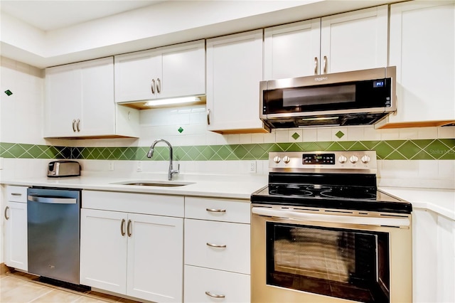 kitchen featuring backsplash, sink, light tile patterned floors, appliances with stainless steel finishes, and white cabinets