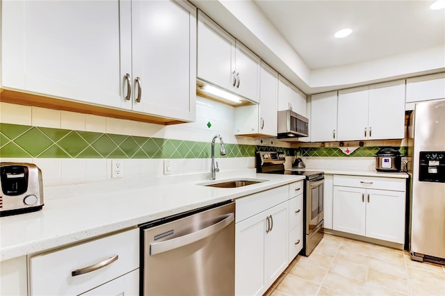 kitchen with tasteful backsplash, white cabinets, sink, and stainless steel appliances