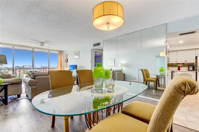 dining room with ceiling fan, floor to ceiling windows, a textured ceiling, and light hardwood / wood-style flooring