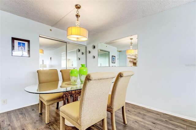 dining space with hardwood / wood-style flooring and a textured ceiling