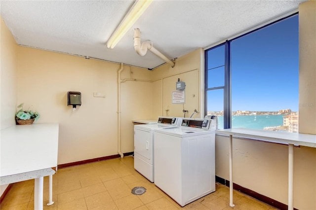 laundry room with washing machine and dryer, a textured ceiling, and a water view