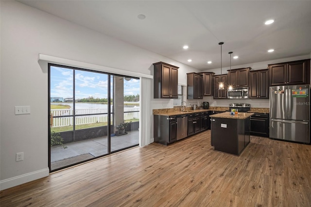 kitchen with light hardwood / wood-style floors, hanging light fixtures, stainless steel appliances, and a kitchen island