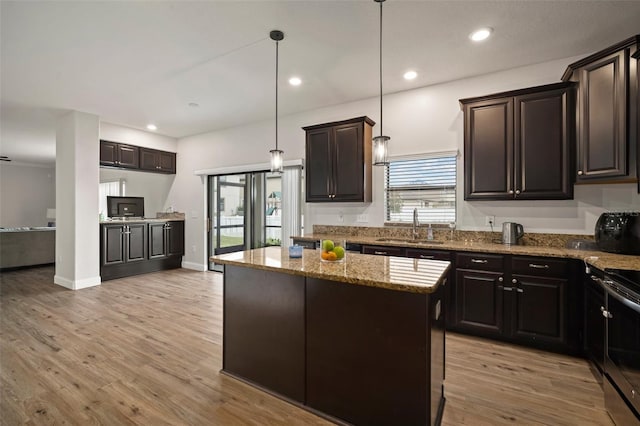 kitchen featuring a center island, light hardwood / wood-style floors, sink, hanging light fixtures, and electric stove