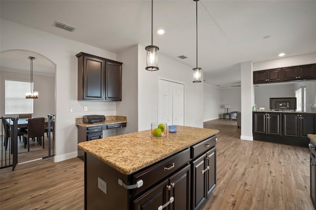 kitchen featuring decorative light fixtures, light wood-type flooring, dark brown cabinets, and a kitchen island