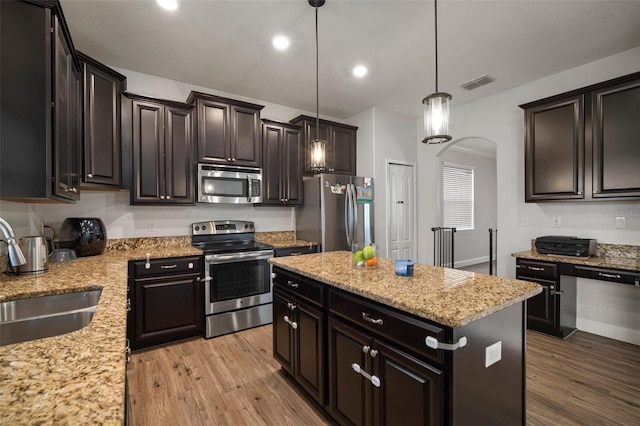 kitchen featuring a kitchen island, stainless steel appliances, light hardwood / wood-style floors, sink, and hanging light fixtures