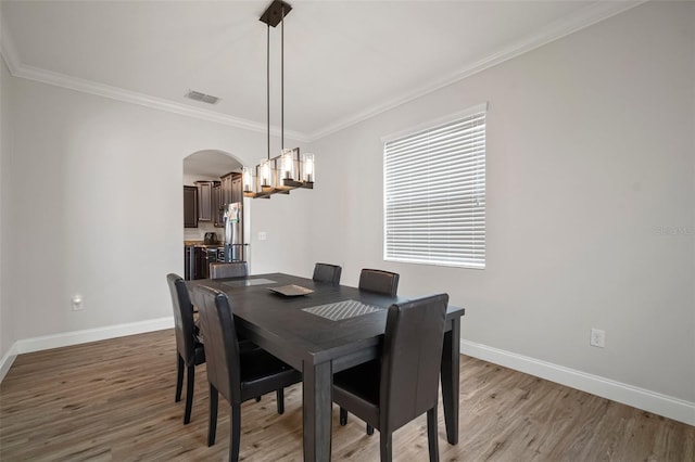 dining area with crown molding and light wood-type flooring