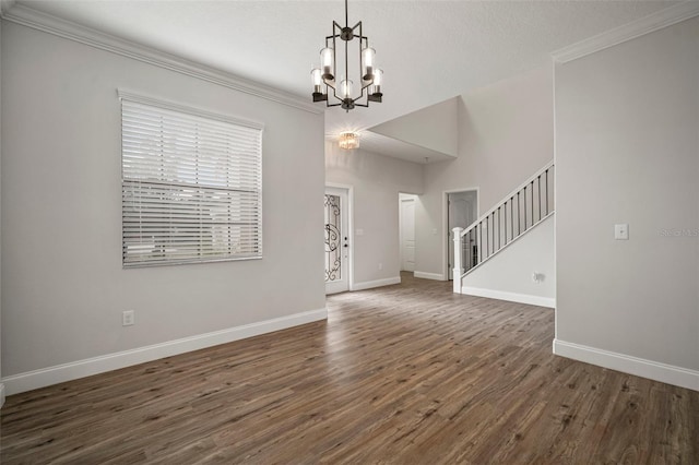 unfurnished living room featuring dark wood-type flooring, a notable chandelier, and ornamental molding