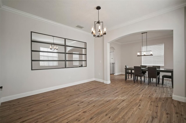 dining area with hardwood / wood-style flooring, ornamental molding, and an inviting chandelier