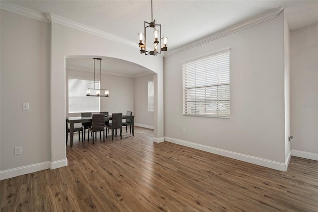 dining space with dark hardwood / wood-style flooring, crown molding, and an inviting chandelier