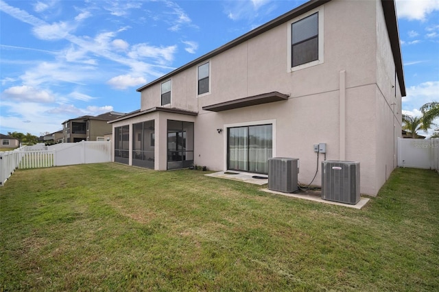 back of property with central air condition unit, a lawn, and a sunroom