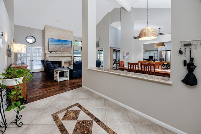 kitchen featuring french doors, stainless steel fridge, a tiled fireplace, and hanging light fixtures