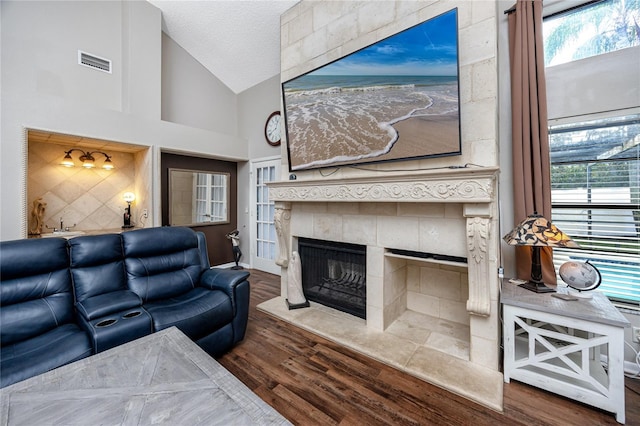 living room featuring high vaulted ceiling, dark hardwood / wood-style floors, a wealth of natural light, a fireplace, and a textured ceiling