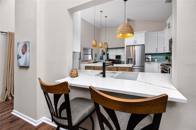 kitchen with hanging light fixtures, kitchen peninsula, white cabinets, and appliances with stainless steel finishes