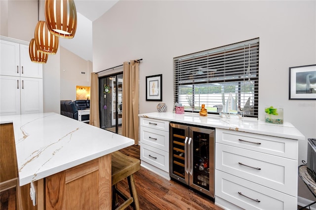 kitchen with white cabinets, light stone countertops, a breakfast bar, and beverage cooler