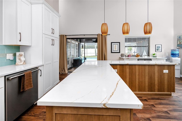 kitchen featuring a kitchen island, decorative light fixtures, tasteful backsplash, dishwasher, and white cabinets