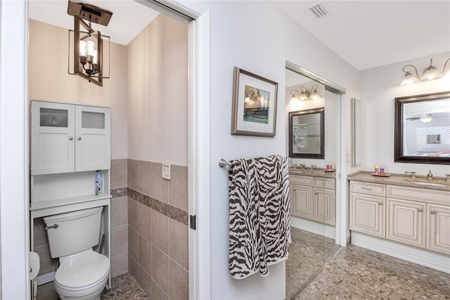 bathroom featuring vanity, tile walls, and toilet