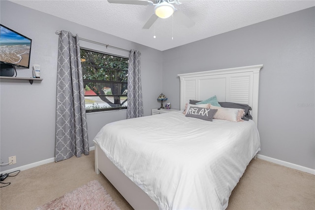 bedroom featuring light carpet, a textured ceiling, and ceiling fan