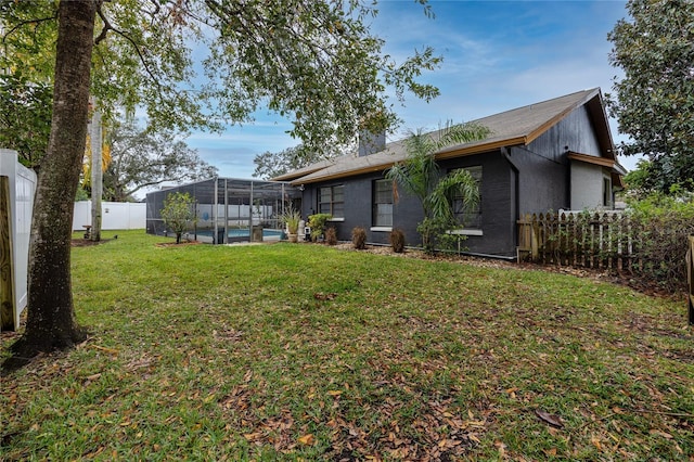 rear view of house featuring a fenced in pool, a lanai, and a lawn