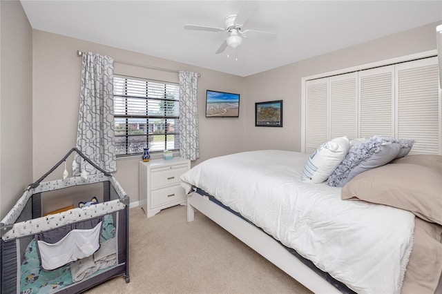 bedroom featuring ceiling fan, light colored carpet, and a closet