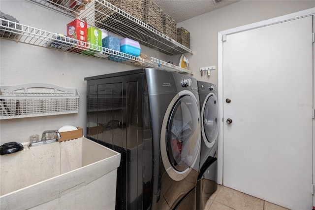 clothes washing area featuring washer and clothes dryer, sink, a textured ceiling, and light tile patterned floors