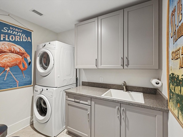 laundry area featuring cabinets, stacked washer and clothes dryer, and sink