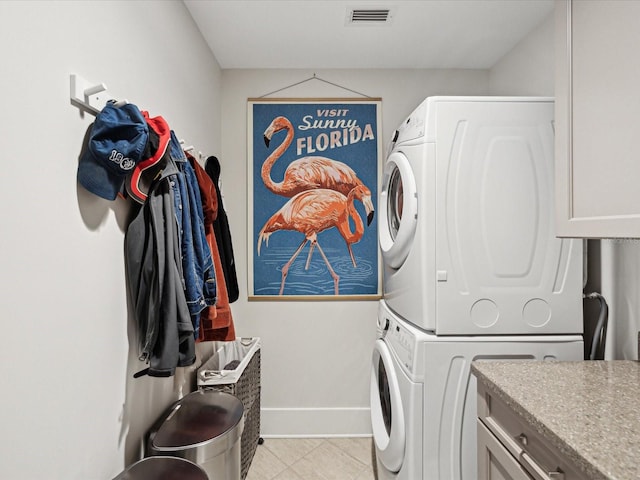 clothes washing area featuring cabinets and stacked washer / dryer