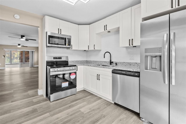 kitchen with light stone counters, sink, white cabinetry, and stainless steel appliances